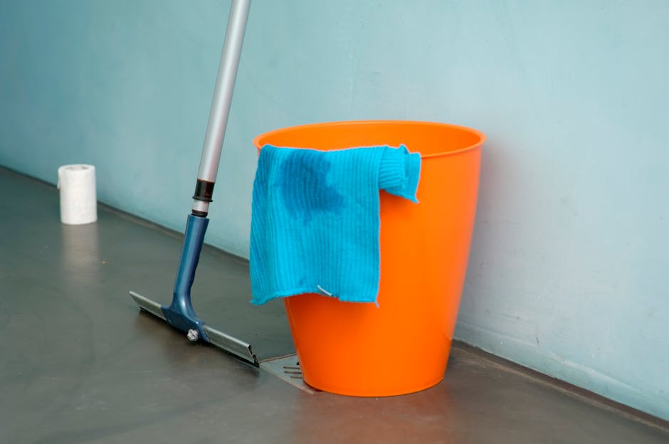 A clean, empty room with light-colored wooden flooring and beige walls illuminated by natural light coming through a window. On the floor, there is a wooden window blind installation kit, including a 